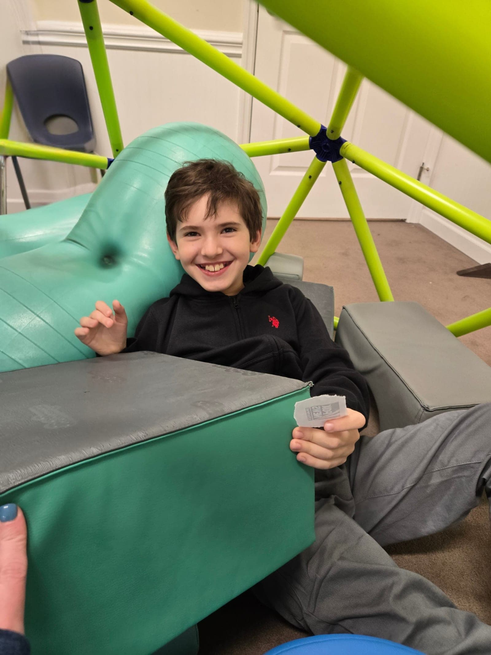 A smiling boy relaxing in the climbing dome during an ABA therapy session