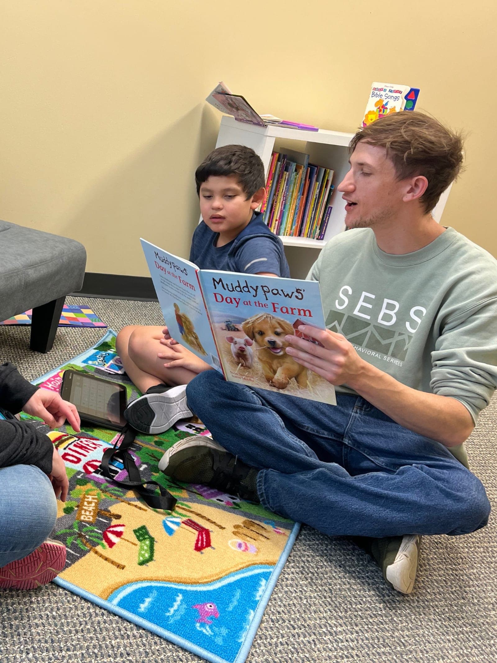 A SEBS team member reading a book with a child during an in-clinic session